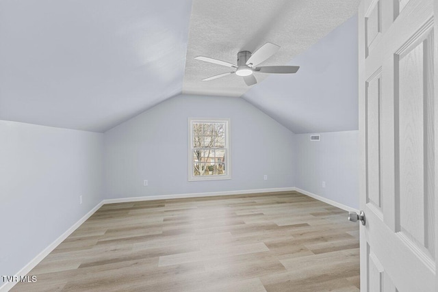 bonus room featuring a textured ceiling, light wood-style flooring, and baseboards