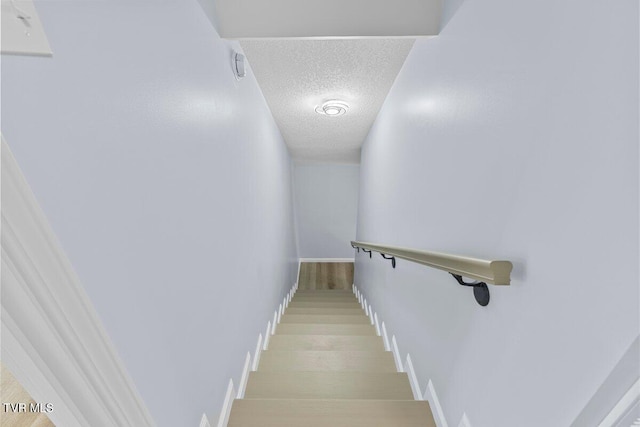 stairs with baseboards, a textured ceiling, and wood finished floors