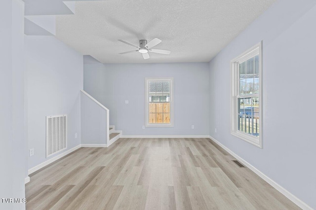 spare room featuring light wood finished floors, stairway, and visible vents