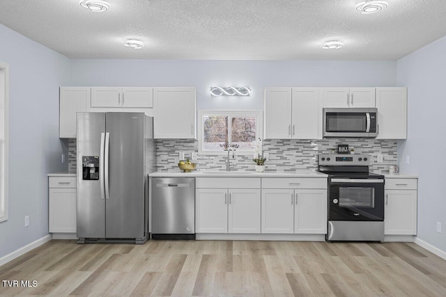 kitchen with appliances with stainless steel finishes, white cabinets, and light countertops