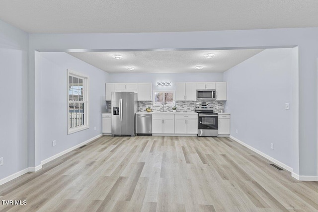 kitchen with white cabinetry, appliances with stainless steel finishes, light countertops, and decorative backsplash