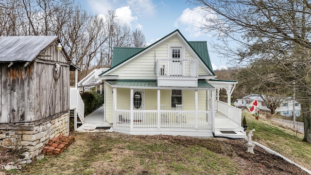 back of house with a yard, metal roof, a porch, and an outbuilding