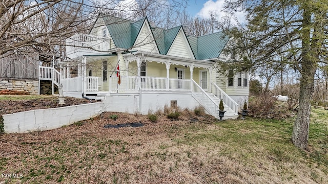 view of front of house featuring metal roof, a porch, stairway, and a front yard