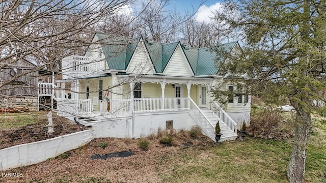 view of front of home with covered porch, stairs, and metal roof