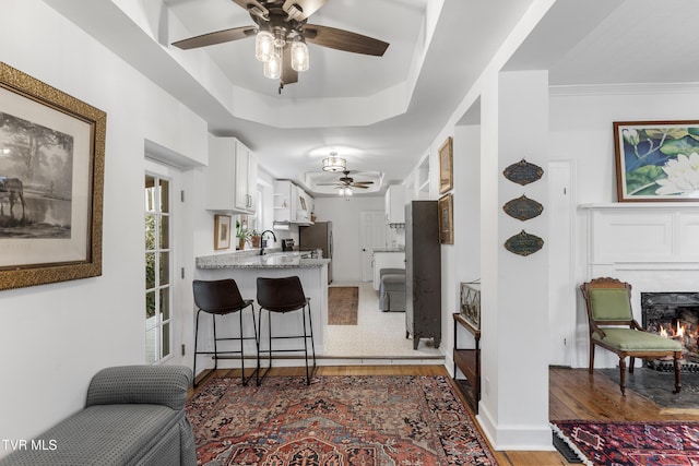 kitchen featuring a sink, white cabinets, a lit fireplace, freestanding refrigerator, and dark wood-style floors