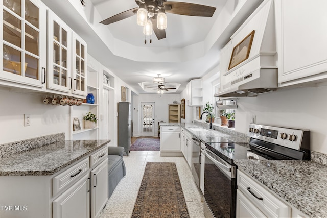 kitchen with light stone counters, appliances with stainless steel finishes, glass insert cabinets, white cabinets, and a sink