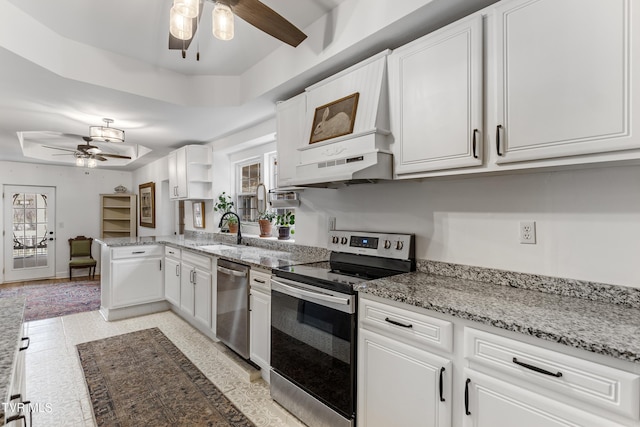 kitchen with under cabinet range hood, a sink, white cabinetry, appliances with stainless steel finishes, and a raised ceiling