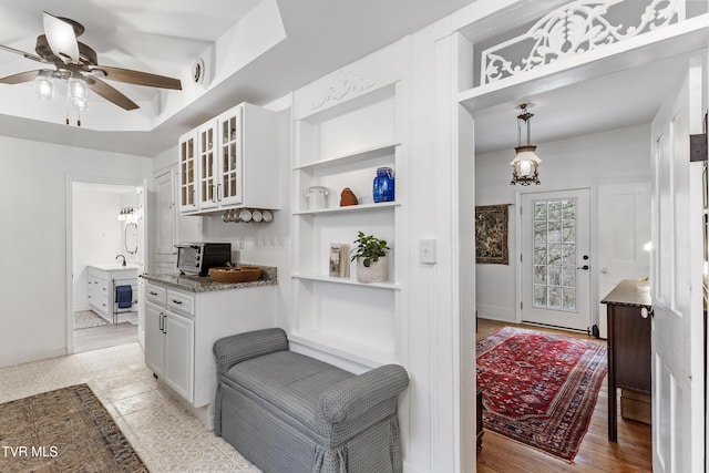 kitchen featuring open shelves, glass insert cabinets, white cabinetry, ceiling fan, and dark stone countertops