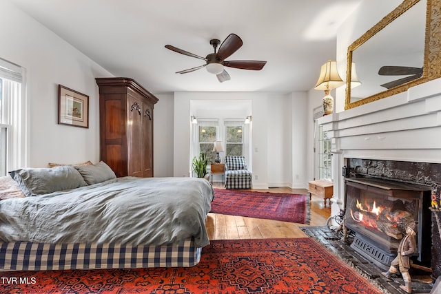 bedroom with baseboards, a fireplace, wood finished floors, and access to exterior