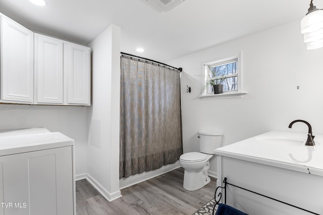 bathroom with shower / tub combo with curtain, toilet, vanity, wood finished floors, and independent washer and dryer