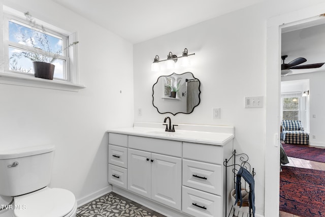 ensuite bathroom featuring a wealth of natural light, ensuite bath, vanity, and toilet