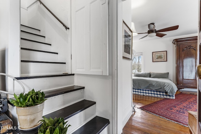 stairs with a ceiling fan and wood finished floors