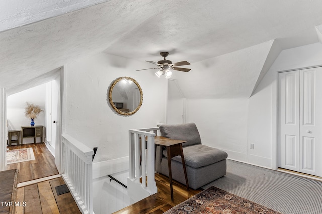 living area with visible vents, a ceiling fan, lofted ceiling, dark wood-style flooring, and a textured ceiling