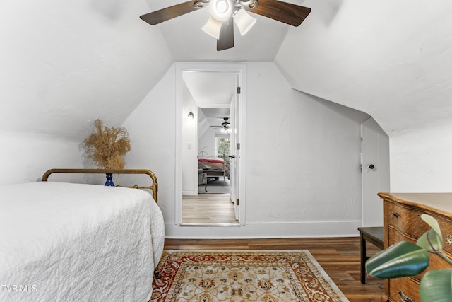 bedroom with dark wood-style floors, lofted ceiling, ceiling fan, and baseboards