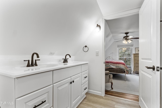 bathroom with double vanity, connected bathroom, a sink, and wood finished floors