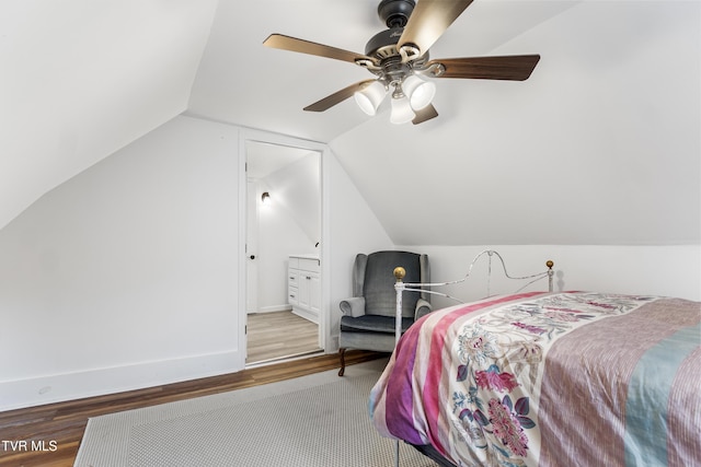 bedroom with baseboards, vaulted ceiling, and wood finished floors