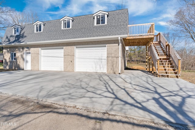 exterior space with a detached garage, roof with shingles, stairs, a deck, and stucco siding