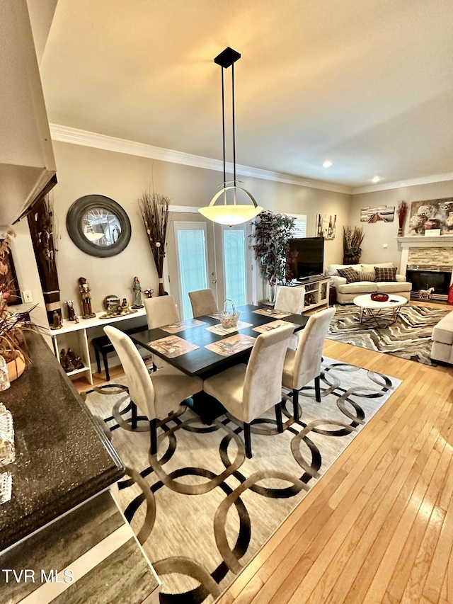 dining area featuring crown molding, a fireplace, and hardwood / wood-style flooring