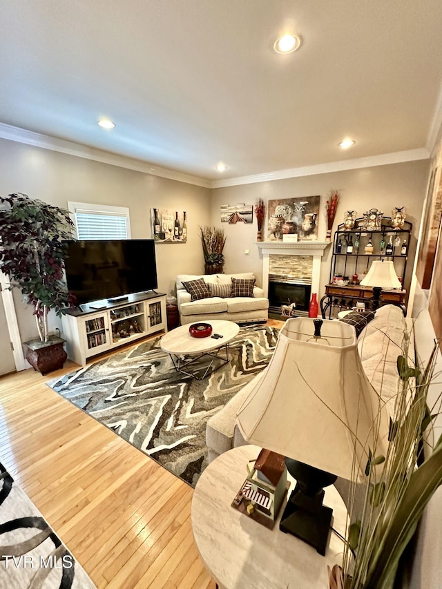 living room with hardwood / wood-style floors, a fireplace, recessed lighting, and crown molding