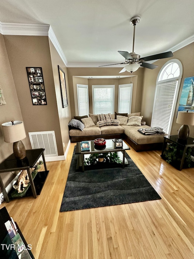 living area featuring plenty of natural light, crown molding, visible vents, and wood finished floors