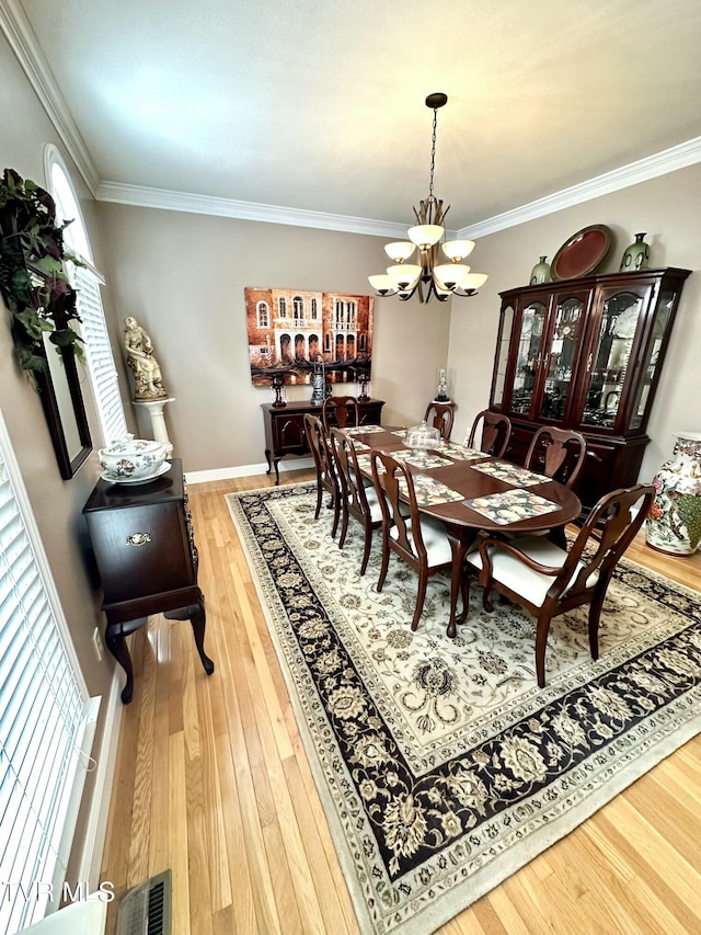 dining space with ornamental molding, wood-type flooring, visible vents, and an inviting chandelier