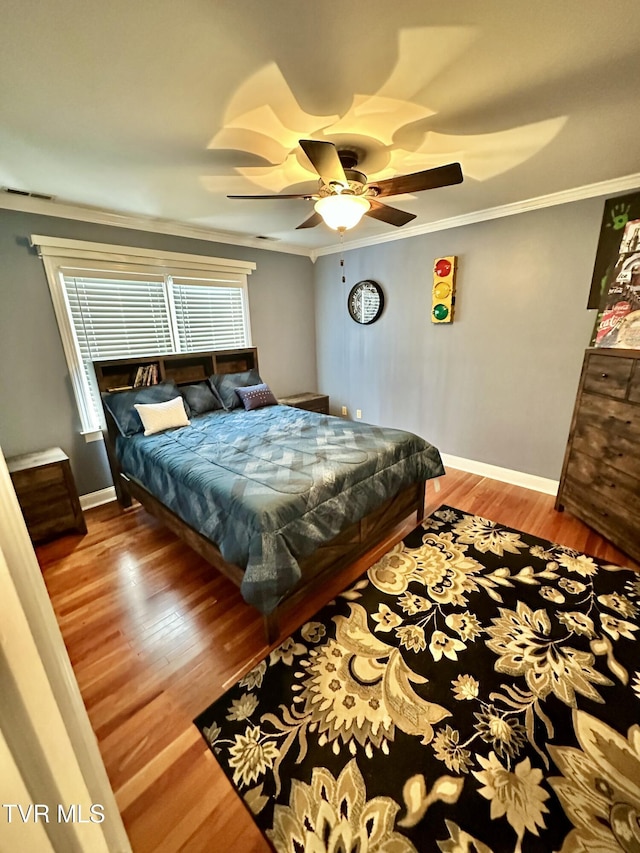 bedroom with a ceiling fan, crown molding, baseboards, and wood finished floors