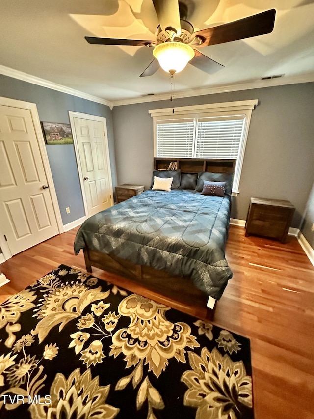 bedroom with ornamental molding, ceiling fan, baseboards, and wood finished floors