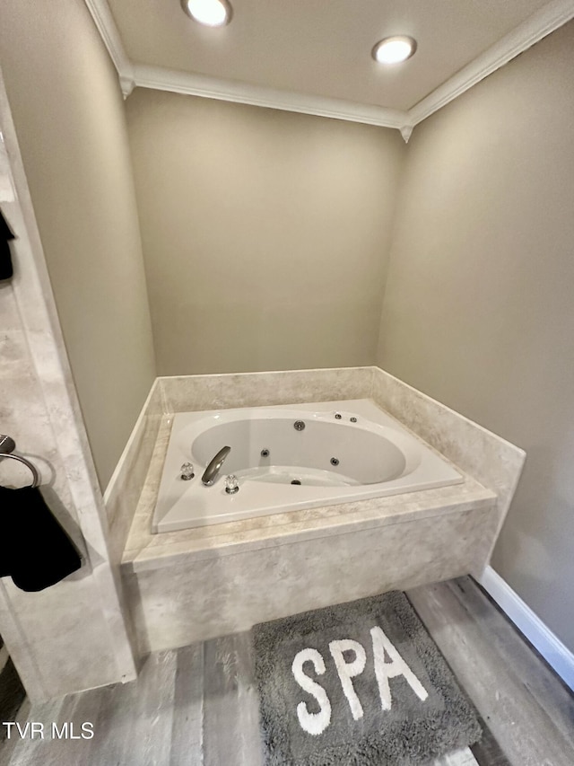 bathroom with a whirlpool tub, ornamental molding, and wood finished floors