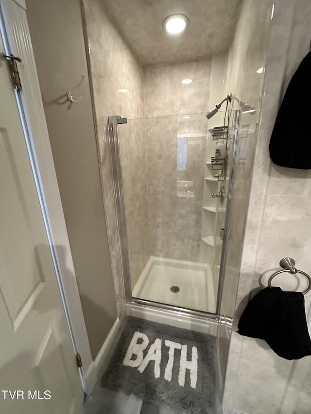 full bathroom with a shower stall and baseboards