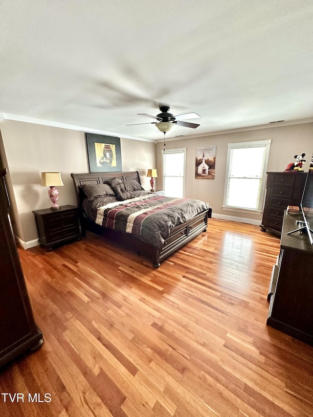 bedroom with ornamental molding, light wood-style flooring, baseboards, and a ceiling fan