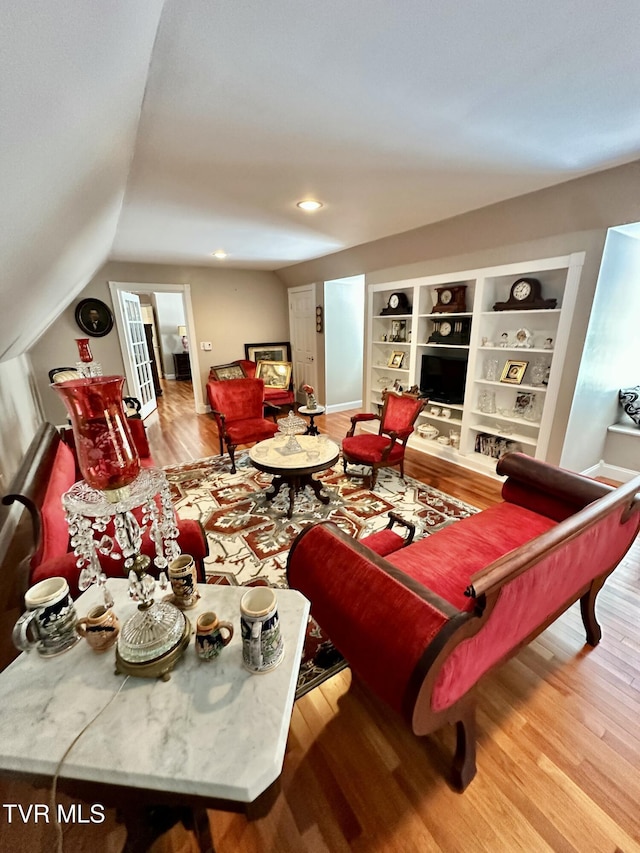 living room with vaulted ceiling, recessed lighting, wood finished floors, and built in features