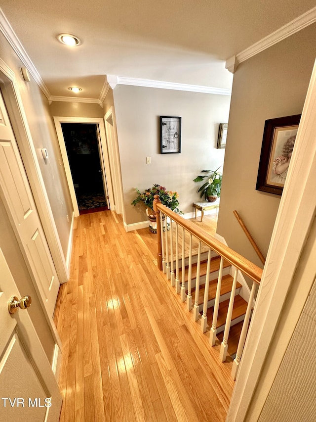 hallway featuring stairway, light wood-style flooring, baseboards, and crown molding