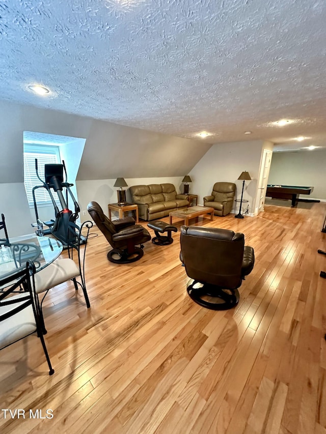 living room with lofted ceiling, a textured ceiling, and light wood finished floors