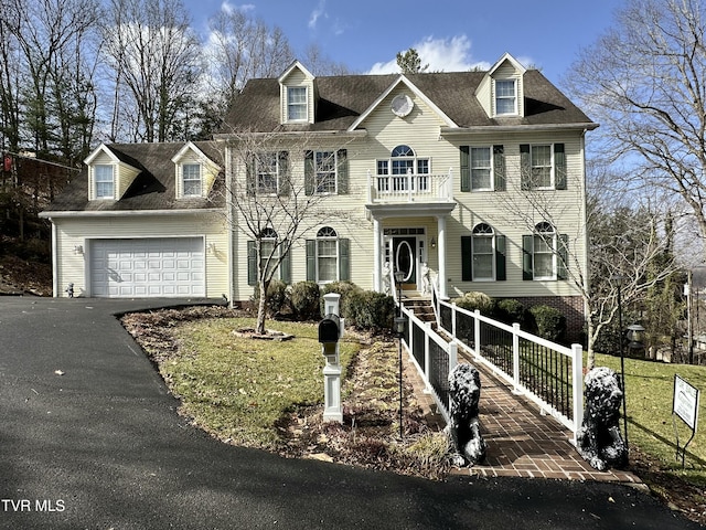 georgian-style home with a garage, driveway, a fenced front yard, and a balcony