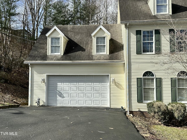 view of front of home featuring driveway, an attached garage, and roof with shingles