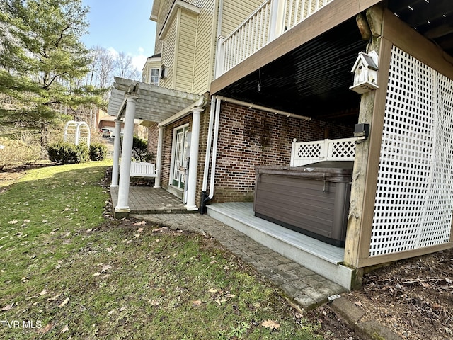 view of property exterior featuring brick siding, a yard, and a hot tub