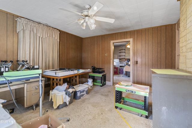 misc room featuring ceiling fan and wood walls