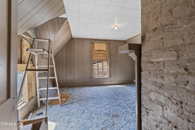 bonus room featuring lofted ceiling and wood walls