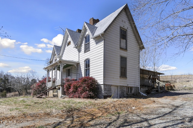 view of home's exterior featuring a porch, a shingled roof, and a chimney