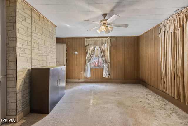 unfurnished room featuring ceiling fan and wood walls