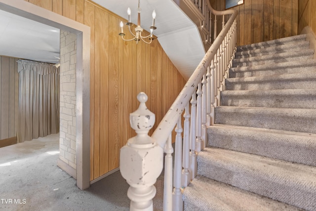 stairway featuring wooden walls and a chandelier