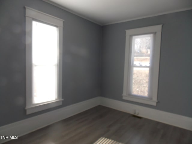 empty room with a healthy amount of sunlight, dark wood-style floors, and baseboards