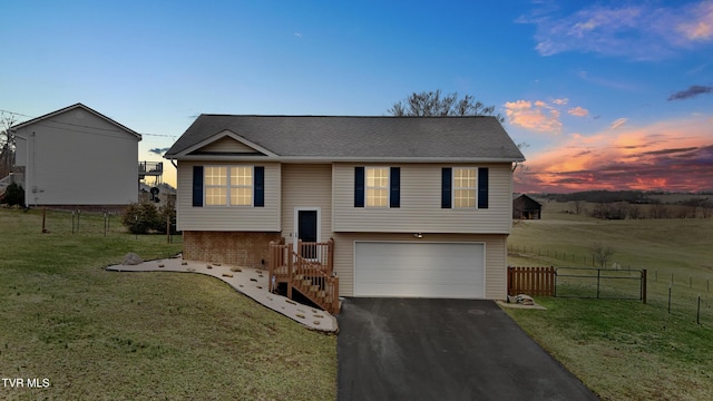 split foyer home featuring driveway, a garage, fence, and a yard