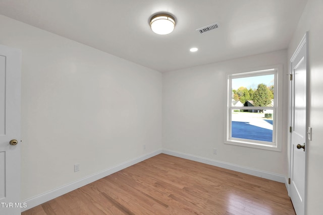 empty room with light wood-type flooring, visible vents, and baseboards