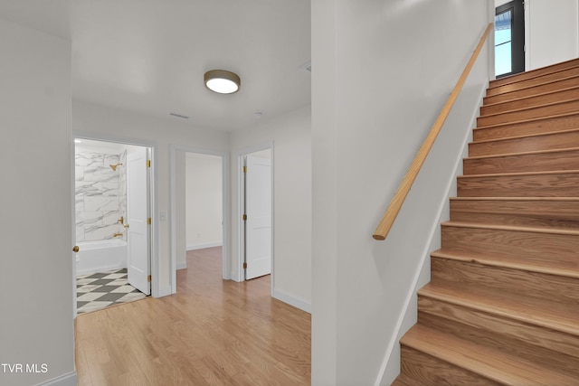 staircase featuring wood finished floors, visible vents, and baseboards