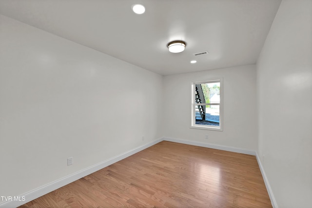 unfurnished room featuring light wood finished floors, visible vents, and baseboards