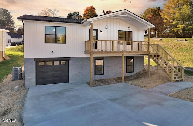 view of front of house with concrete driveway, central AC, an attached garage, and stairs