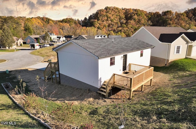 rear view of property featuring stairway, roof with shingles, a lawn, and a deck