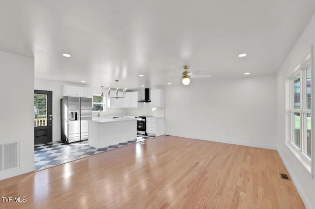 unfurnished living room with light wood-style floors, a healthy amount of sunlight, and visible vents