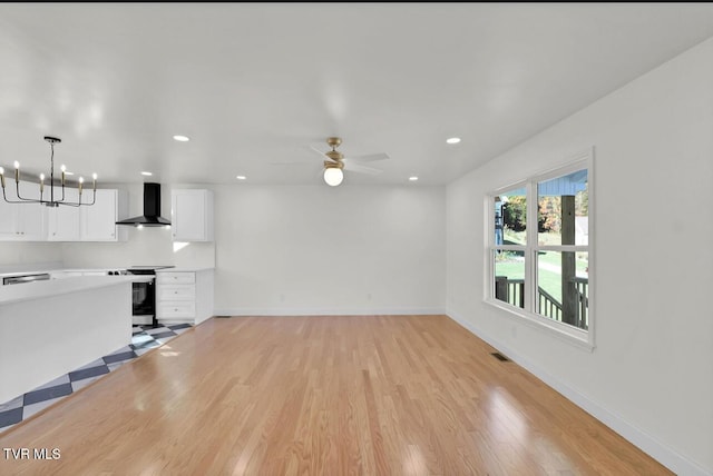 unfurnished living room with light wood finished floors, recessed lighting, baseboards, visible vents, and ceiling fan with notable chandelier